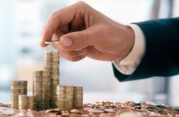 Hand of a mid adult man, wearing a siut, is stacking Euro coins