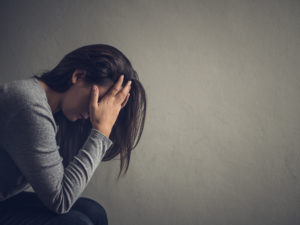 Mujer deprimida sentada en una silla en una habitación oscura en casa. Lonly , sad, emotion concept.